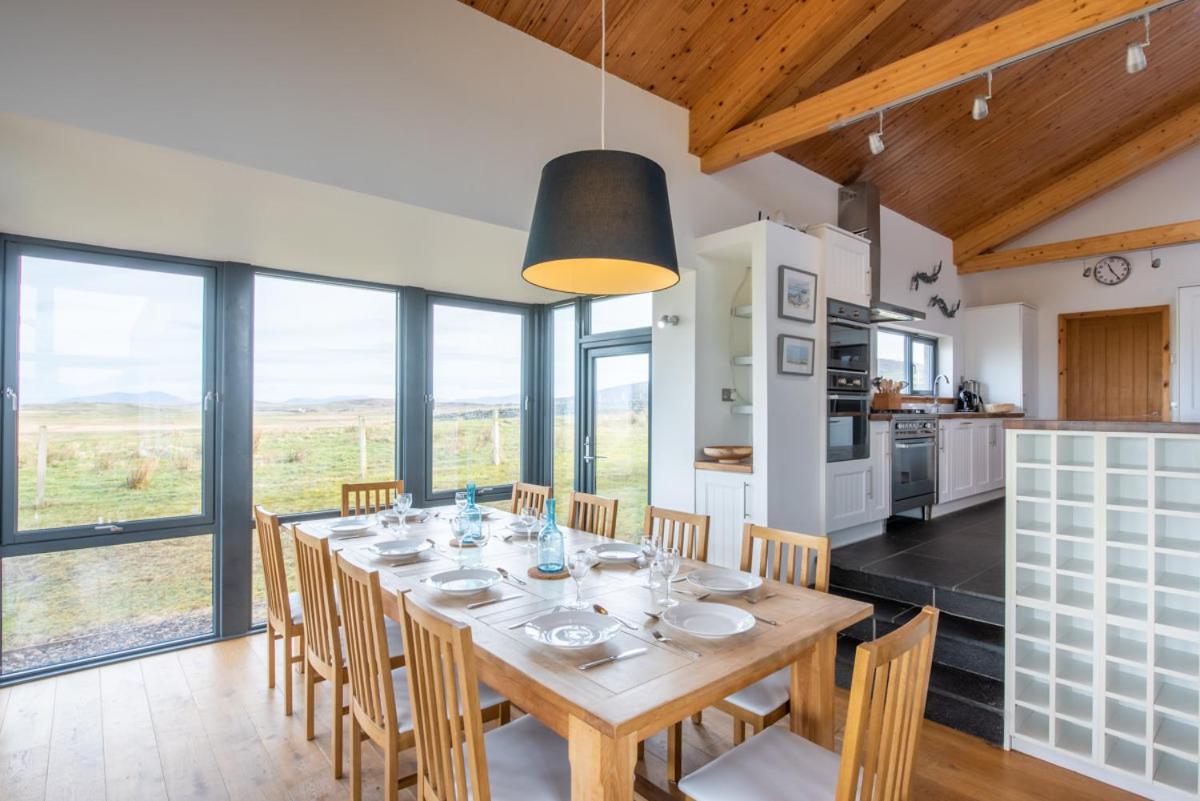 a kitchen and dining room with a table and chairs at Clachan Lodge in Trumisgarry