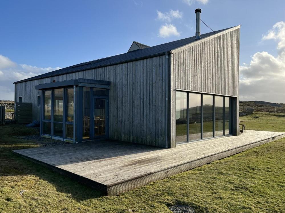 a small house with a wooden deck in a field at Clachan Lodge in Trumisgarry