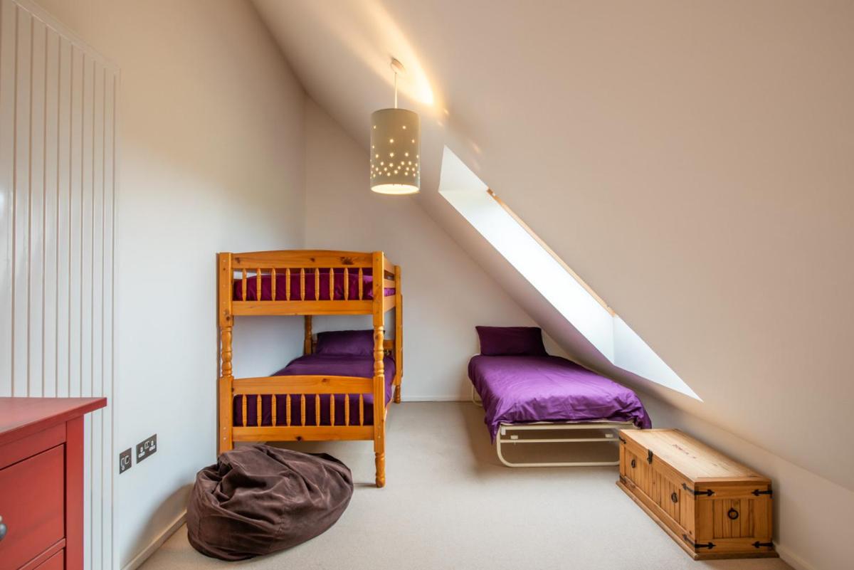a attic room with a bunk bed and a ladder at Clachan Lodge in Trumisgarry