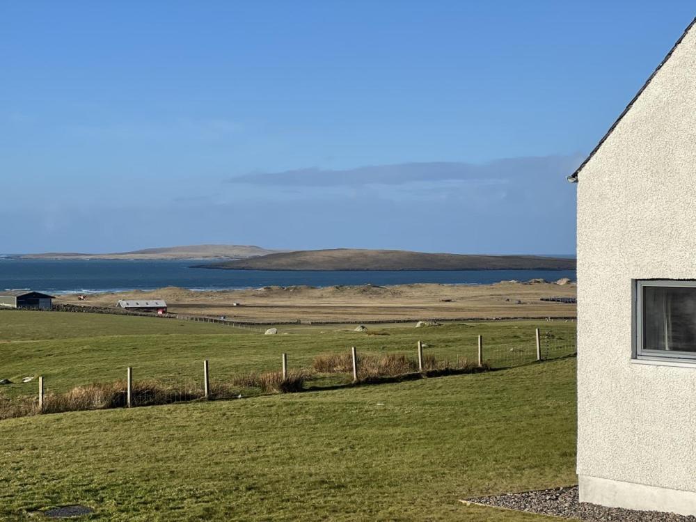 a building next to a field and a fence at Clachan Lodge in Trumisgarry