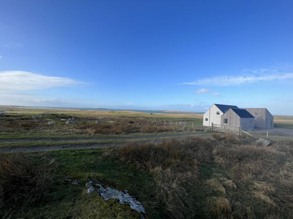 a white house in the middle of a field at Clachan Lodge in Trumisgarry