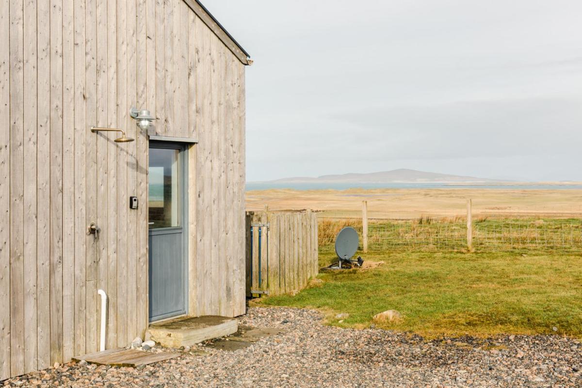 a barn with a door and a chair in a field at Clachan Lodge in Trumisgarry