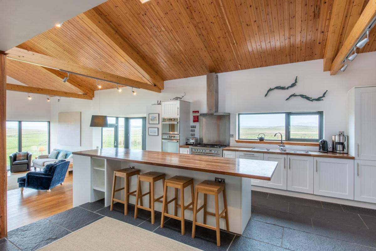 a kitchen with a large island with bar stools at Clachan Lodge in Trumisgarry