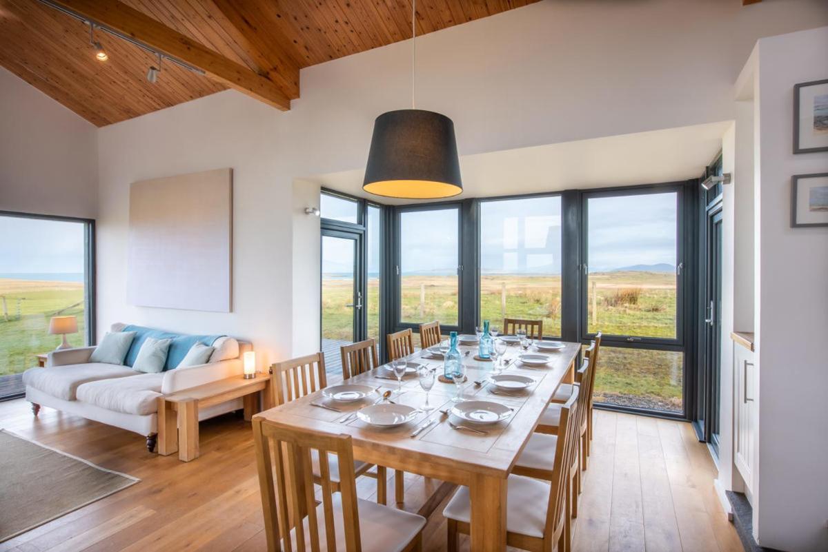 a dining room with a table with chairs and a couch at Clachan Lodge in Trumisgarry
